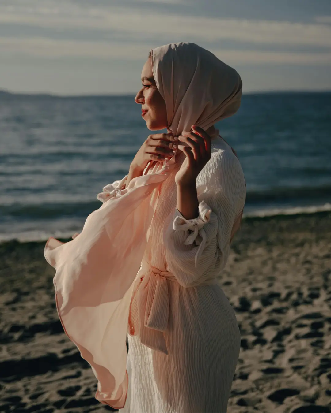 muslim woman walking on beach wearing modest dress and headscarf